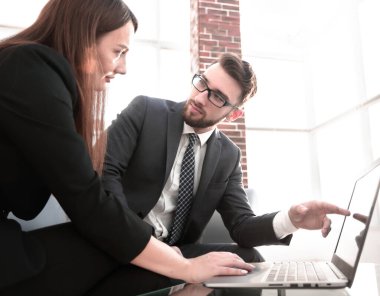 Güzel genç iş ortakları bir dizüstü bilgisayar kullanarak, belgeleri tartışırken ve ofiste çalışırken gülümseyen