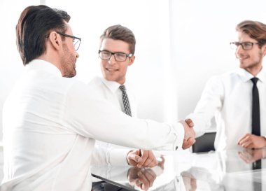 İş ortakları masada otururken el sıkışırlar.