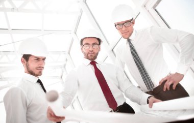 Üç mimar yeni bir projenin çizimlerini tartışıyor.