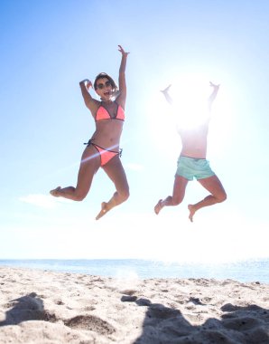 Kumsalda zıplayan mutlu bir çiftin fotoğrafı..