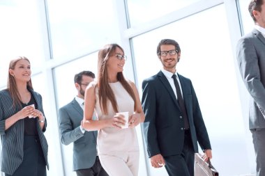 Bir grup iş adamı çalışma gününde ofis koridorundan geçiyor.