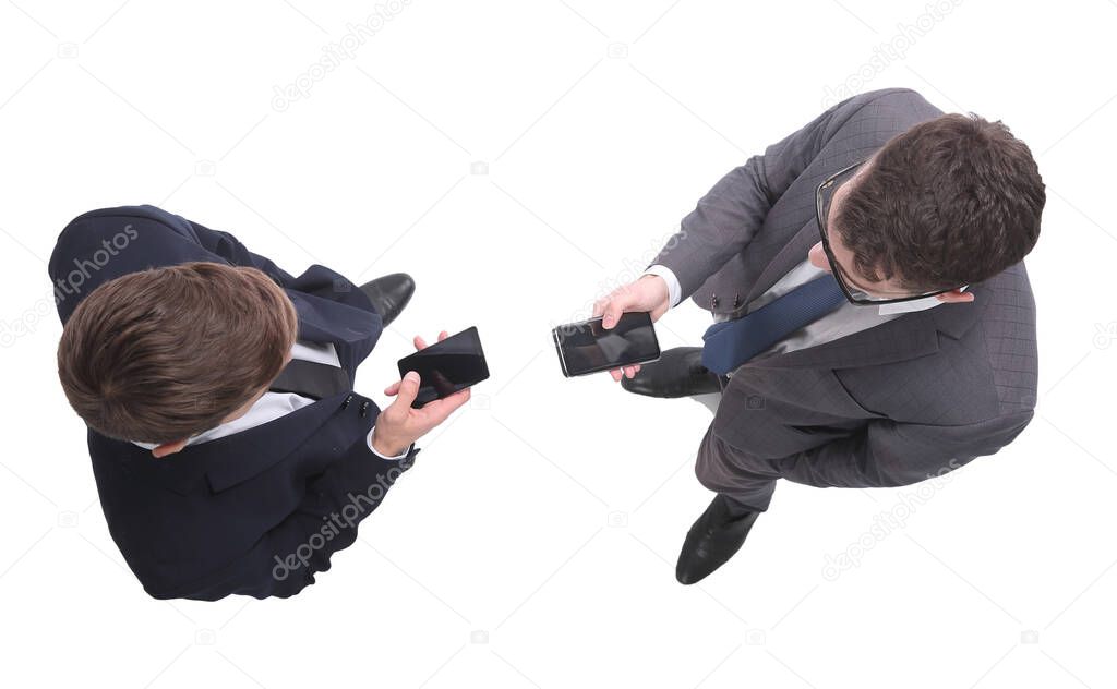 top view . two businessmen looking at the screens of their smartphones . isolated on white background.