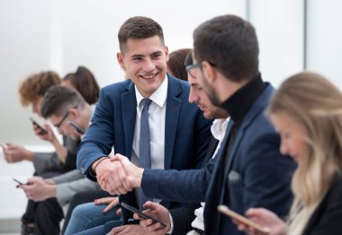 Kapat. Genç çalışanlar el sıkışarak birbirlerini selamlıyorlar.