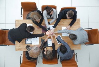 Üst Manzara. İş ekibi masaüstünde el ele tutuşuyor. Takım çalışması kavramı