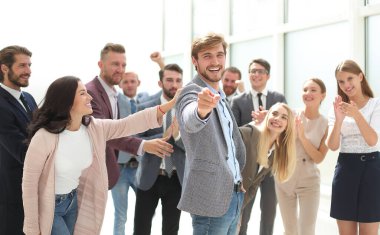 İş arkadaşlarının arasında durup seni işaret eden mutlu bir iş adamı. başarı kavramı