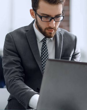 Bir dizüstü bilgisayarda office arka plan ile iş yapan ciddi adam.