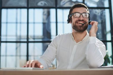 Gülümseyen yakışıklı genç erkek çağrı merkezi operatörü.