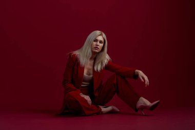 Kırmızı arka planda kırmızı elbiseli sarışın bir kadının portresi.