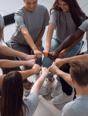 Bir grup benzer fikirli genç insan ellerinden bir daire çiziyor. Birlik kavramı.