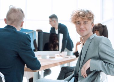 Ofisteki bir iş toplantısı sırasında masada oturan genç bir çalışan..