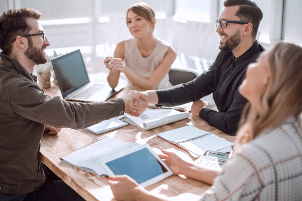 улыбающиеся деловые партнеры, пожимающие руки на деловой встрече. бизнес концепция