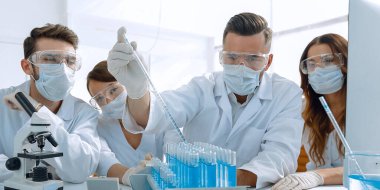 Genç tıp doktorları laboratuarda test tüpleri ve mikroskop ile çalışıyoruz