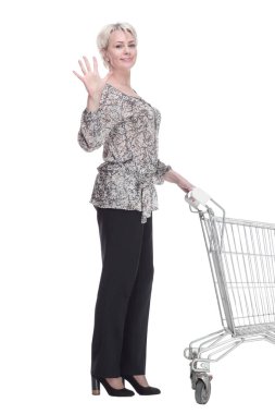 Yan görünüş. Alışveriş arabalı zarif genç bayan sana bakıyor. beyaz arkaplanda izole edilmiş.