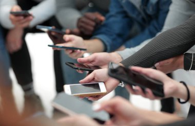 Kapat. Akıllı telefonları olan bir grup genç daire çiziyor.