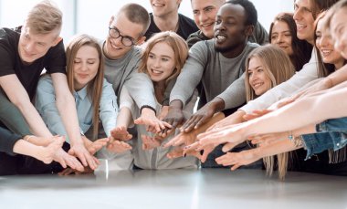 Kapat. Bir grup gülümseyen genç insan ellerini birleştiriyor.