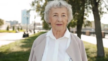 Gevşemiş yaşlı bayanın, yaz günü açık havada durduğu ağır çekim portresi.