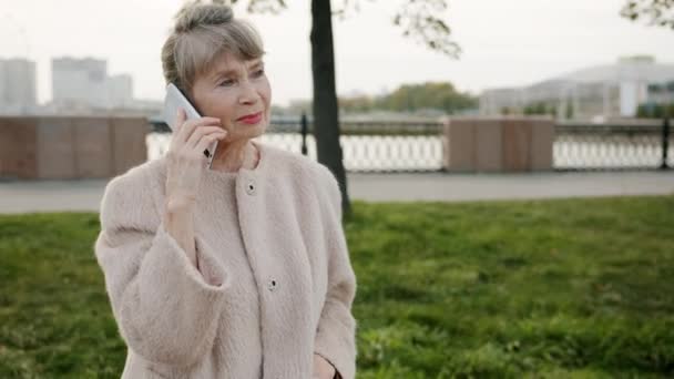 Portret starszej siwowłosej kobiety rozmawiającej przez telefon komórkowy stojącej na ulicy miasta — Wideo stockowe