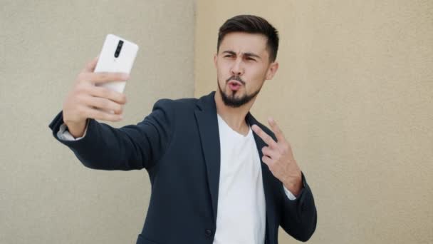 Handsome mixed race man posing for smart phone camera taking selfie outdoors — Stock Video