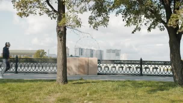 Vista lateral del deportista maduro con auriculares corriendo al aire libre en el terraplén del río — Vídeos de Stock