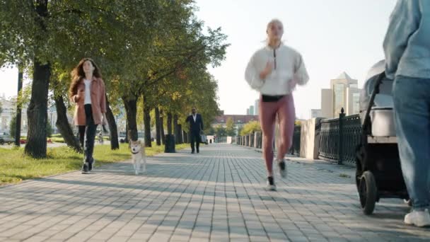 Skupina městských lidí muži a ženy pohybující se podél chodníků v moderním městě — Stock video