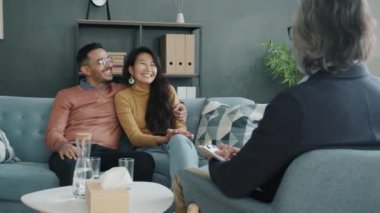 Ofisteki aile danışmanlığı sırasında sohbet eden ve gülen neşeli genç çift.