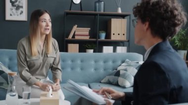 Genç kadın duygularını terapistle paylaşıyor. Modern ofisteki koltukta oturmuş gülümseyen hayattaki sorunları tartışıyor. İnsanlar ve psikoterapi kavramı.