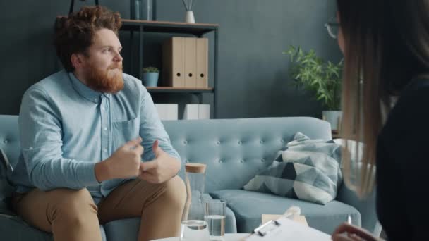 Молодий чоловік спілкується з психотерапевтом під час індивідуальної консультації в офісі — стокове відео