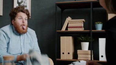 Deli genç adam psikiyatrist randevusu sırasında yüzünü buruşturup yastıkla eğleniyor.