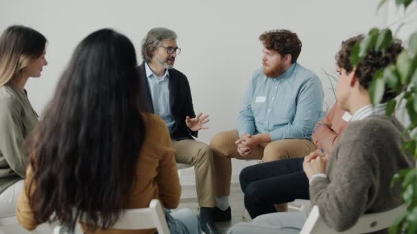 Psicólogo profesional hablando con grupo de pacientes durante reunión de terapia en estudio — Vídeo de stock