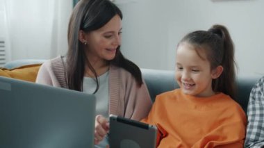 Anne ve kızı tabletin keyfini çıkarırken baba evde akıllı telefon mesajları kullanıyordu.