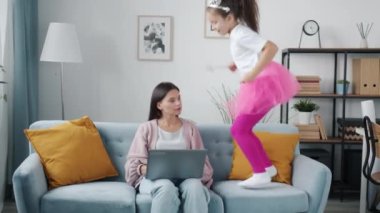 Evde dizüstü bilgisayar kullanmakla meşgul bir anne sinir bozucu bir çocuk zıplıyor ve koşturuyor.