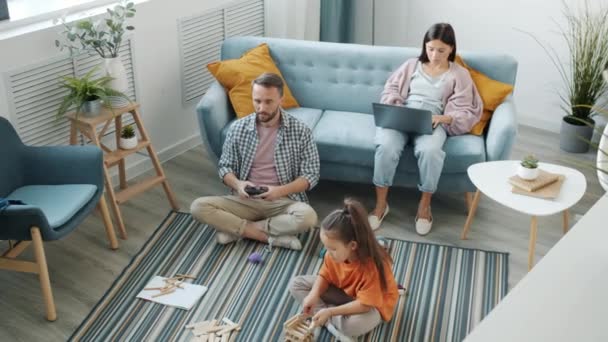 Familie genießt Freizeit zu Hause mit Geräten und Spielen drinnen in gemütlichem Zimmer — Stockvideo