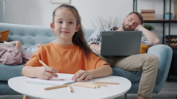 Zpomalený film portrét roztomilé holčičky usmívající se kresba při pohledu na kameru, zatímco rodiče spí — Stock video