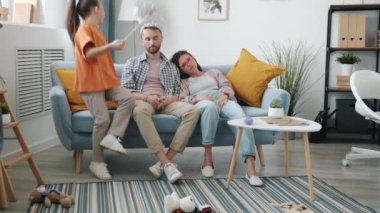 Anne ve baba yorgun bir şekilde kanepede oturuyor ve mutlu görünmüyorlar.