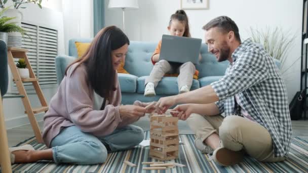 Щаслива мати і батько грають з іграшками, які роблять п'ять під час роботи з ноутбуком — стокове відео