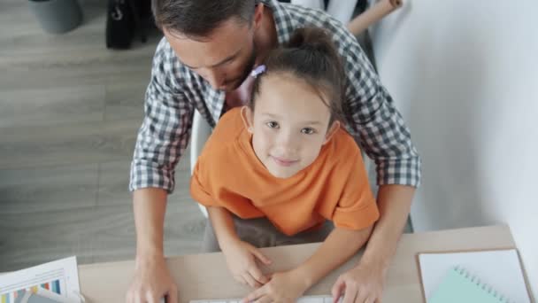 Portret van zorgzame vader werken met pc terwijl klein meisje zitten in zijn schoot op zoek naar camera — Stockvideo
