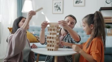 Anne, baba ve kız evlerinde eğlenmek için tahta oyuncaklarla ilginç oyunlar oynuyorlar.
