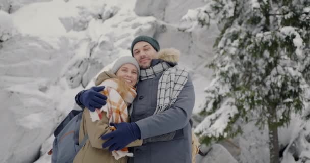 겨울 숲에서 서 카메라를 보며 웃고 있는 행복 한 젊은 부부의 느린 움직임 — 비디오