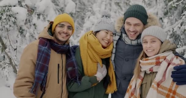 Медленно движущийся портрет радостных мужчин и женщин туристов, смеющихся и смотрящих в камеру в зимнем лесу — стоковое видео