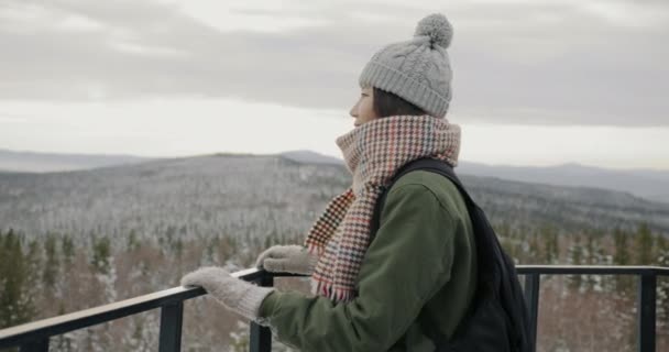 Kvinna asiatisk turist med ryggsäck tittar på hisnande utsikt över vintern tallskog och berg — Stockvideo