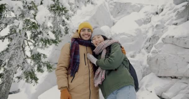 Långsam rörelse porträtt av vackra biracial par stående i vinterskogen leende kramar — Stockvideo