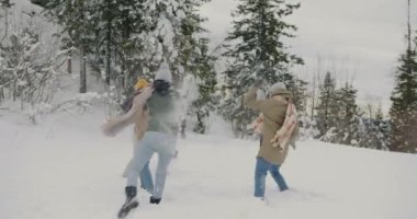 Kışın dışarıda kartopu oynayan heyecanlı gençler birlikte eğleniyorlar.