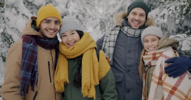 Jeunes gens heureux étudiants debout dans les bois d'hiver étreignant et regardant la caméra — Video