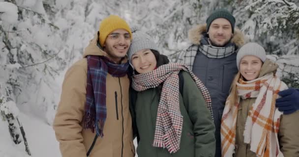 Slow motion porträtt av glada ungdomar stående i vinterskogen kramas njuta av resan — Stockvideo