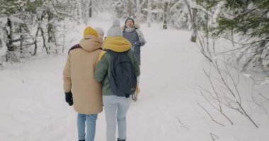 Bir grup öğrenci kışın ormanda yürüyor ve kartopu oynuyorlar. Birlikte eğleniyorlar.