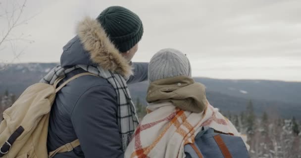 素晴らしい冬の風景を見て、山の中で屋外で話して幸せな若いカップルの肖像画 — ストック動画