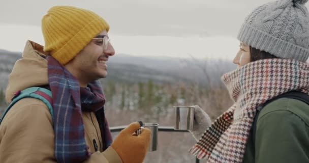 Ευτυχισμένο ζευγάρι τουρίστες clinking μεταλλικά ποτήρια πίνοντας γέλιο και βλέποντας εκπληκτικό τοπίο το χειμώνα — Αρχείο Βίντεο