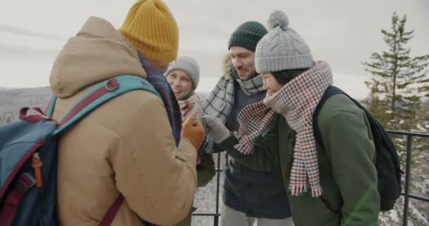 Joyful amigos turistas tazas tintineo tostadas y beber al aire libre en la cubierta de observación en las montañas — Vídeo de stock