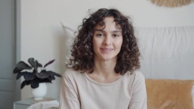 Mutlu bir kızın portresi. Yatakta rahat bir yatak odasında kameraya bakarak gülümsüyor.
