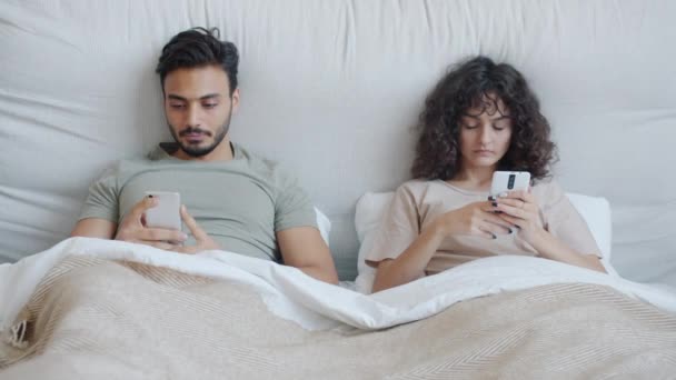 Νεαρή γυναίκα χτυπάει τον Άραβα σύζυγο ενώ αυτός χρησιμοποιεί smartphone στο κρεβάτι — Αρχείο Βίντεο